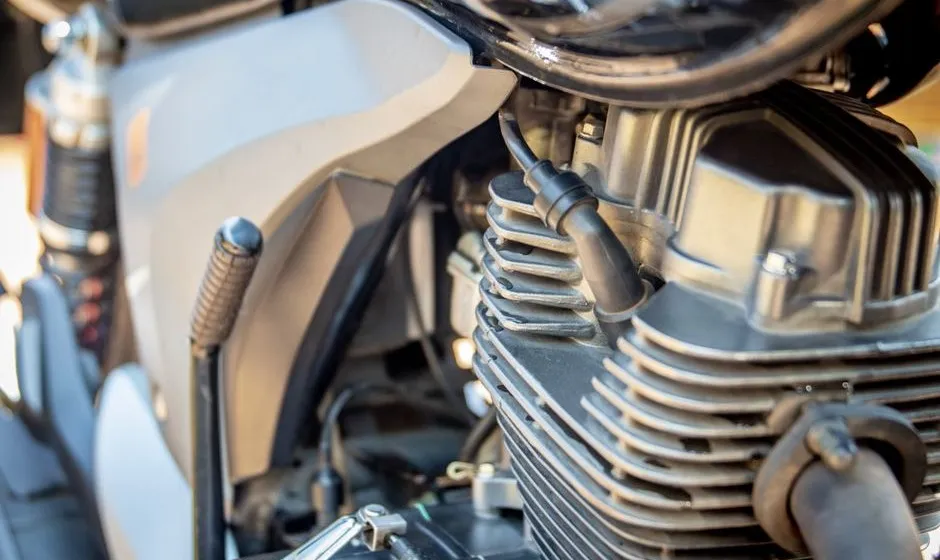 Pièces de scooter 50cc rangées sur un établi d'atelier, courroie et pot d'échappement visibles